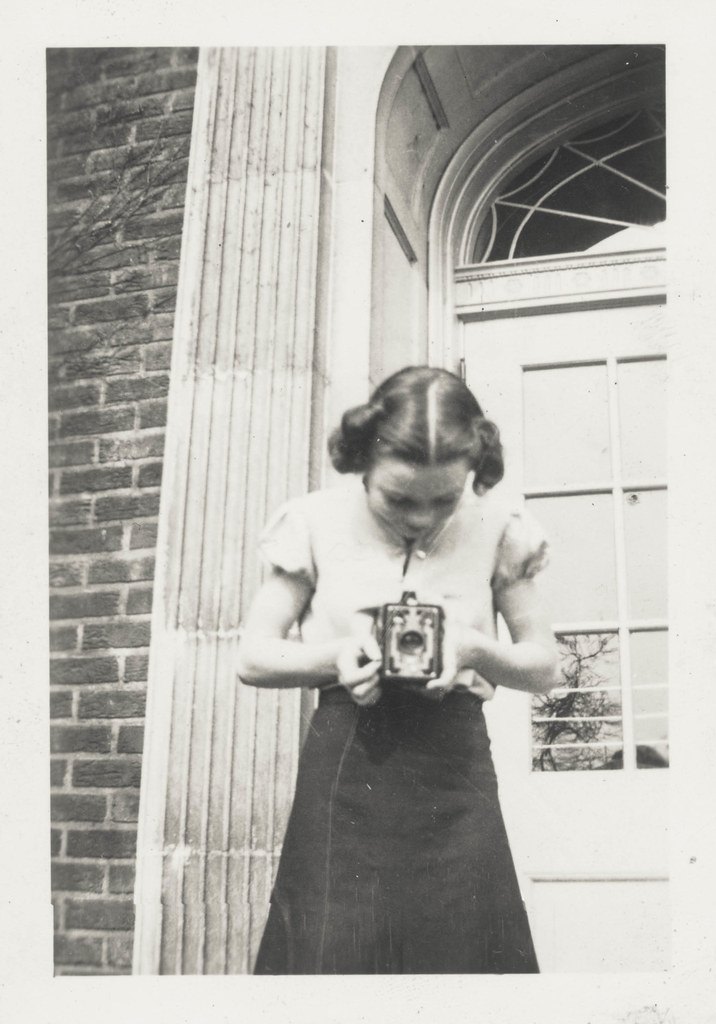 Photographie ancienne en noir et blanc d'une jeune femme tenant un appareil photo, illustration de l'analyse de documents en histoire-géographie au brevet
