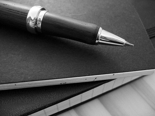 Stylo posé sur un carnet noir, illustration des exercices de grammaire et de conjugaison au brevet